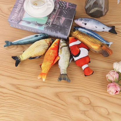Assortment of realistic fish toys in salmon, mackerel, koi, goldfish, carp, and clownfish prints on a wood table with a book and roses