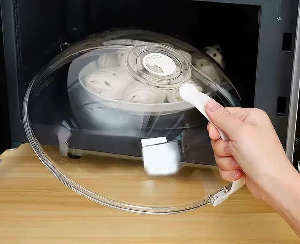 Hand lifting the clear splash guard off a gray bowl of rolled items inside a microwave