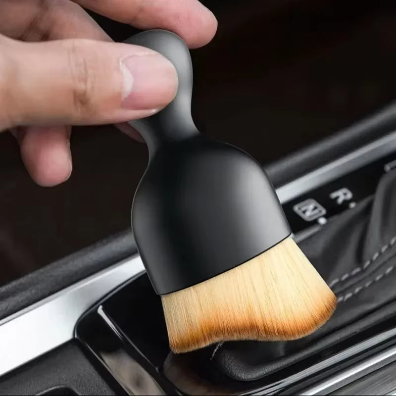 Hand holding the brush over the gear shift console area of a car