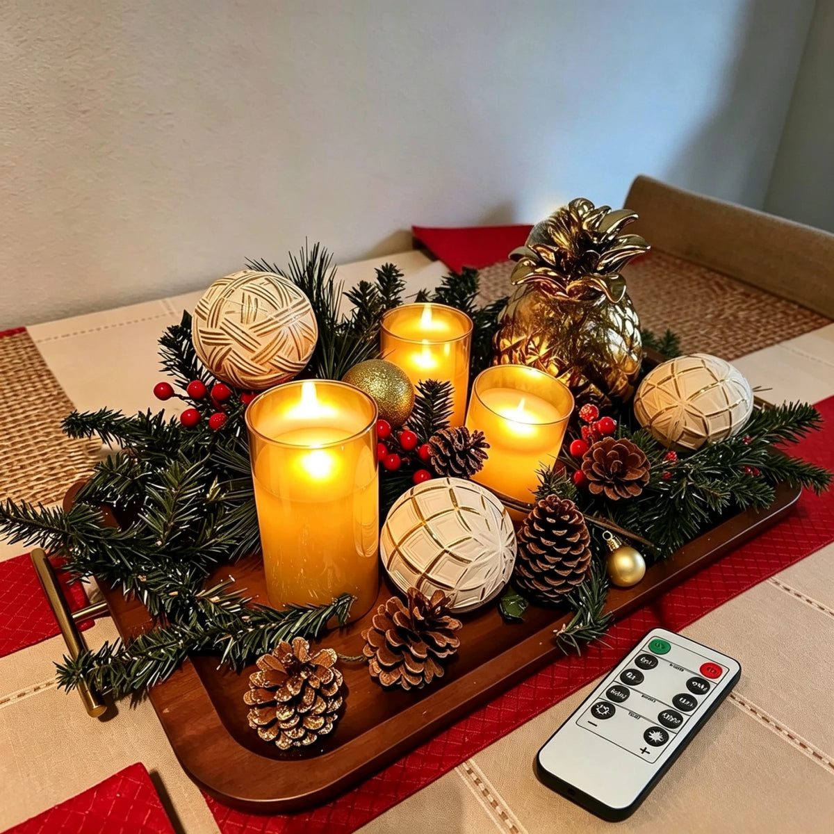 Amber glass LED candles arranged as a holiday centerpiece with pinecones, ornaments and a gold pineapple decoration