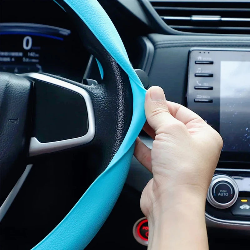 Hand stretching a teal silicone cover onto a steering wheel to demonstrate the stretch-fit installation