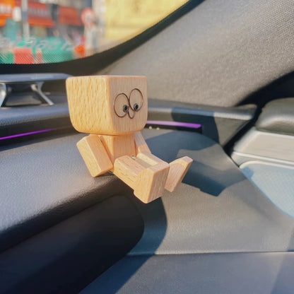 Wooden figurine perched on a car center console near the infotainment screen with a blurred street outside