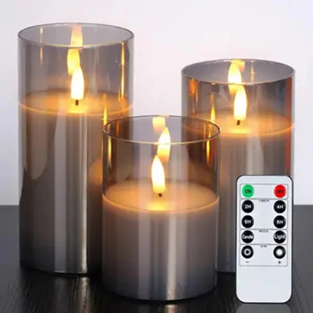 Three smoke-grey glass LED candles with remote control on a dark wood surface