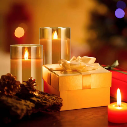 Two amber glass LED candles beside a wrapped gold gift box and a red candle, warm bokeh Christmas background