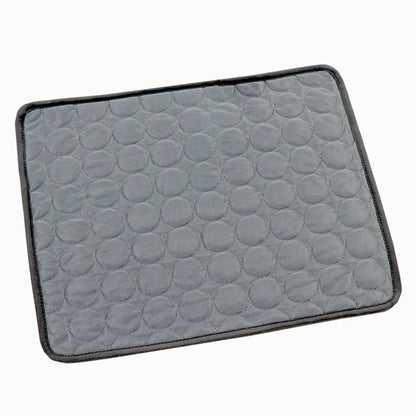 Dark grey quilted cooling gel mat with black trim, laid flat, angled studio shot on white background
