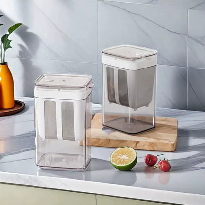 Small and large yogurt strainers on a marble countertop against a tiled wall with a plant and cherries
