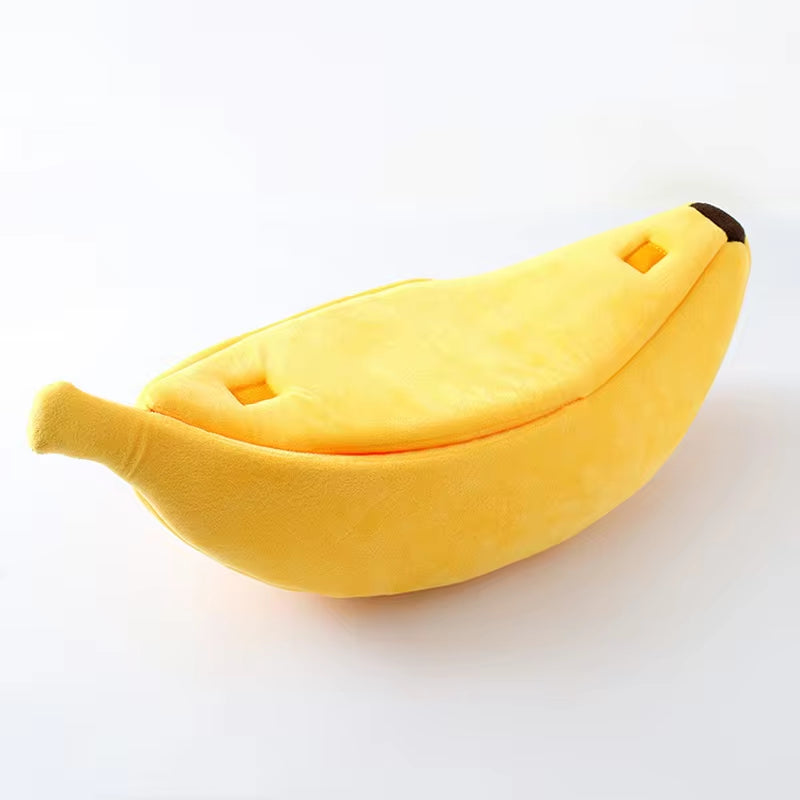 Single closed yellow banana cat bed, angled top view showing peel texture, stem, and dark tip