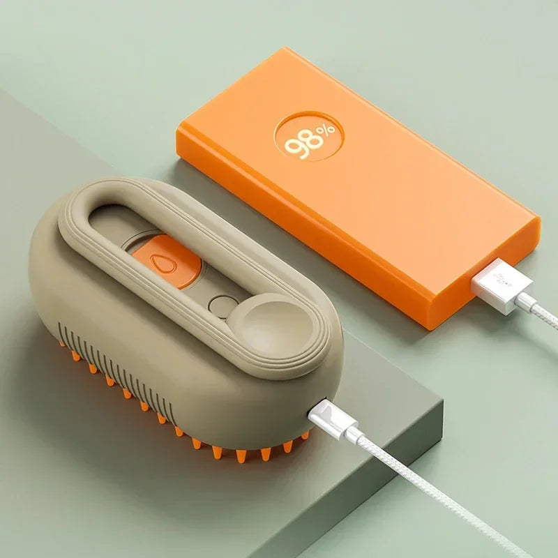 Beige steam grooming brush with orange bristles beside an open orange power bank showing 98% battery, connected by USB-C cable