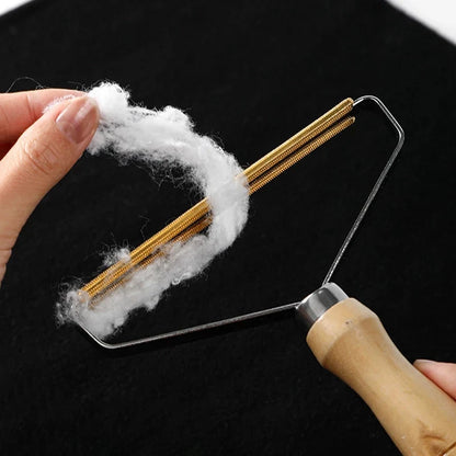 Hand pulling a large tuft of white fluff off the comb's gold teeth over black fabric