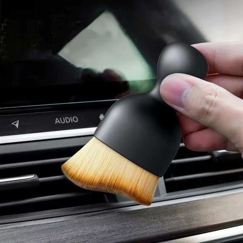 Different angle of a hand pinching the brush handle near the Audio vent on the dashboard
