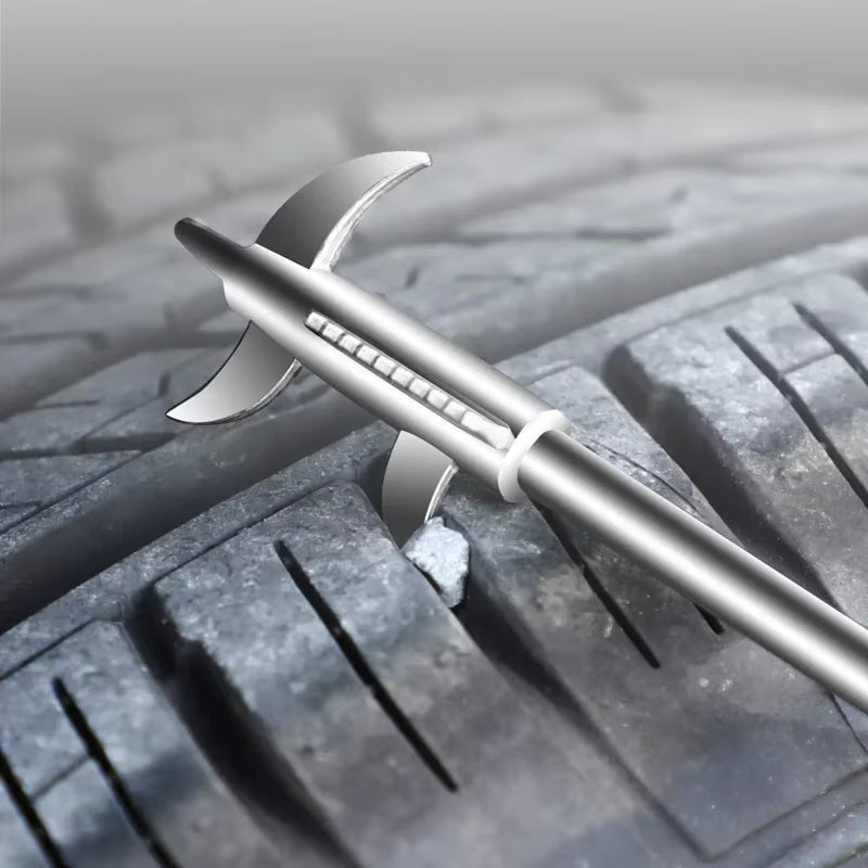 Extreme close-up of the metal hook tip prying a small stone out of a tire tread groove