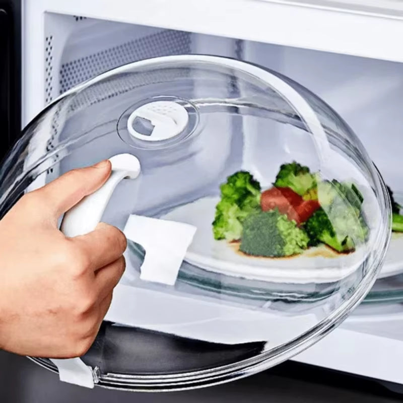 Close-up of the vented splash guard dome over a broccoli and tomato plate, spin knob visible, inside a microwave